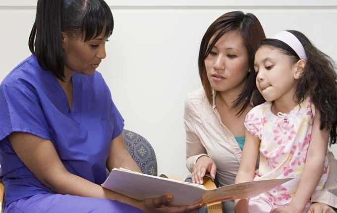 A healthcare professional assists a mother and her daughter.